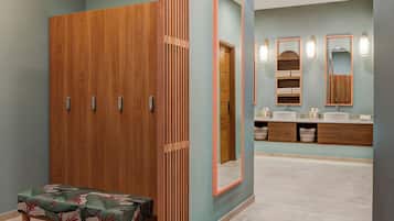 Een badkamer met een houten garderobe, een bankje en een wastafelmeubel met spiegels en planken.
