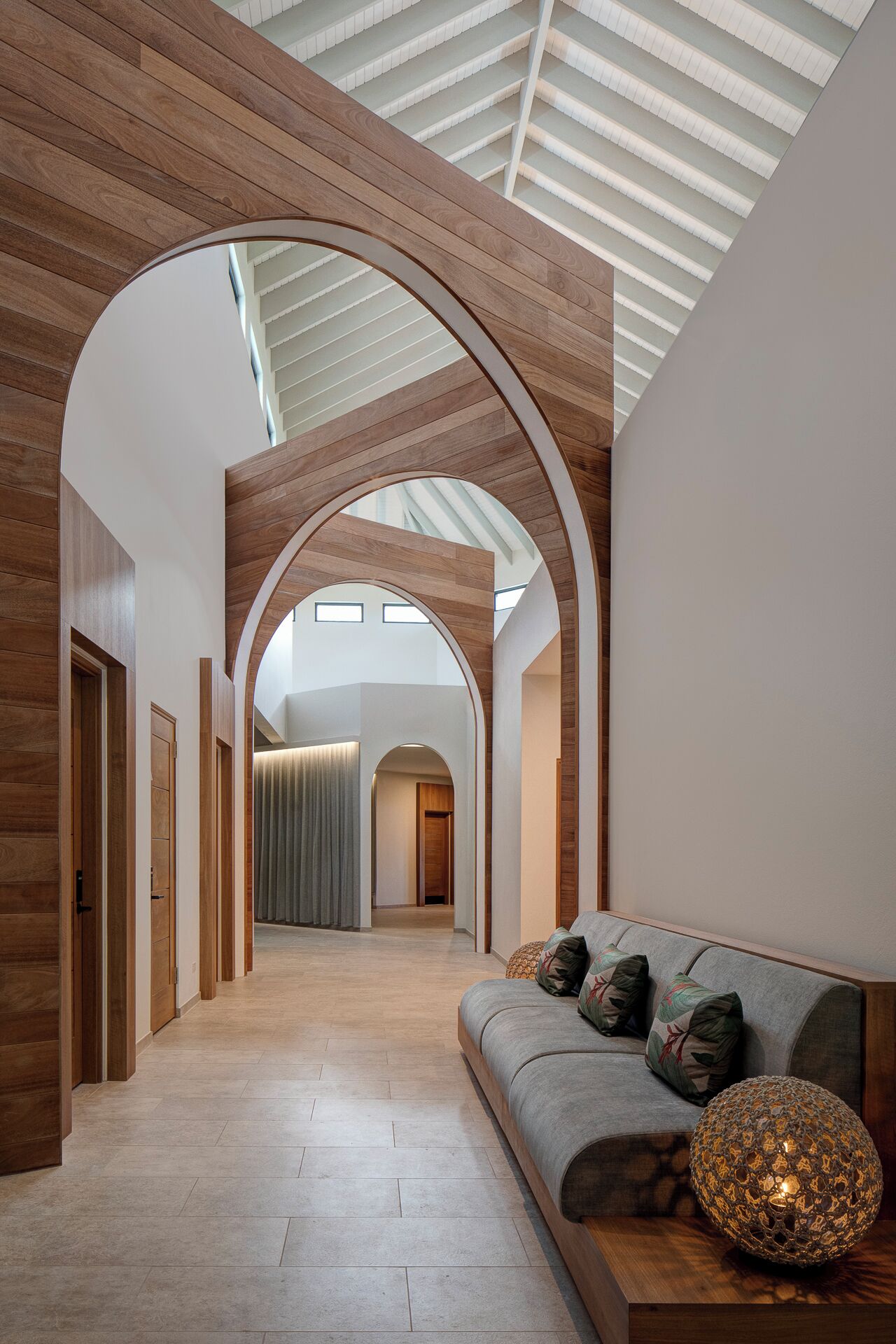 A modern interior with a wooden floor, a sofa with cushions, and a skylight.
