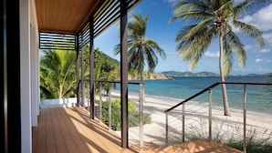 A wooden deck with a view of a beach and palm trees. - Peter Island Resort (Sprat Bay)