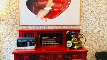 Ein roter Holzbüro mit einem Bilderrahmen, der ein abstraktes Gemälde zeigt, einer Stapel Bücher und einem Vintage-Telefon.