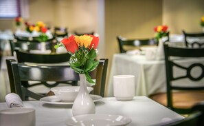 A dining table with a white vase containing flowers, white plates, and a white cup. - West End Washington DC, Tapestry Collection by Hilton (Washington)