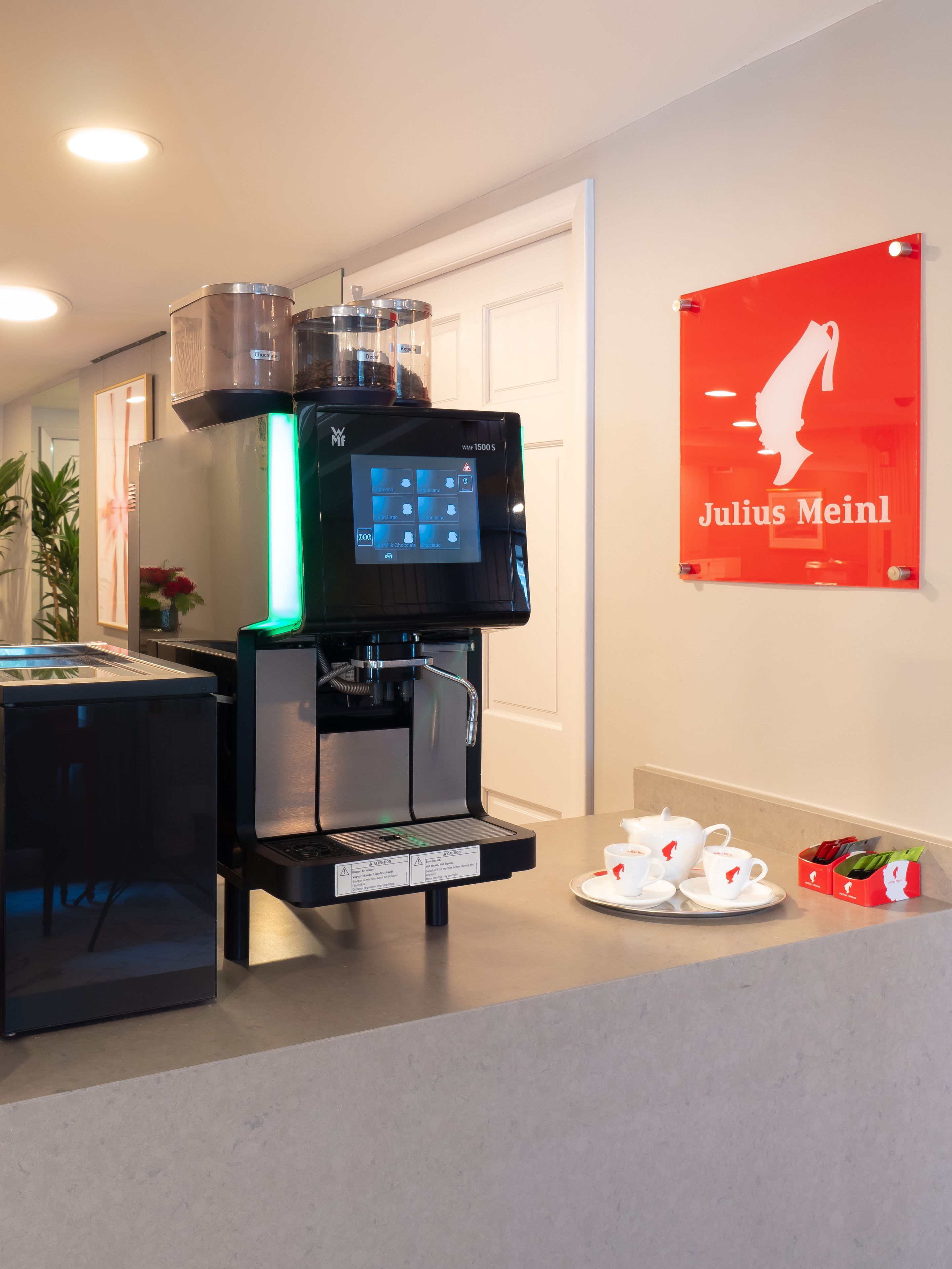 Una máquina de café con pantalla digital y un cartel en la pared.