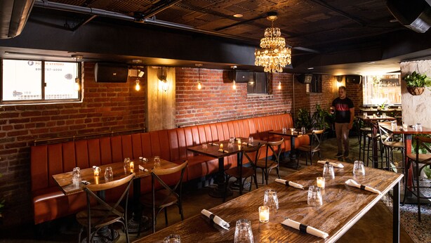 A restaurant interior with brick walls, wooden tables, and leather booths.