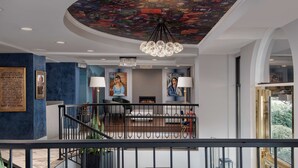 A hotel lobby with a modern design, featuring a staircase, chandeliers, and artwork on the walls.