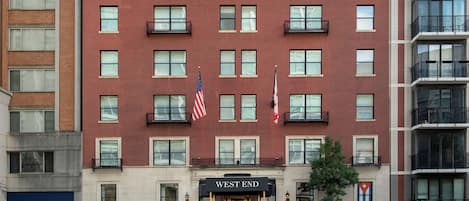 Un hotel de varios pisos con fachada de ladrillo rojo, múltiples balcones y banderas.