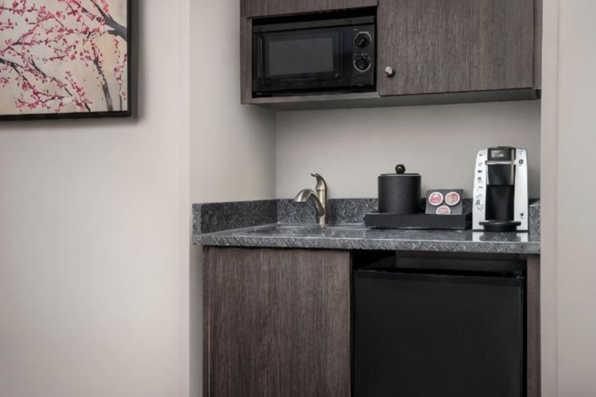 A compact kitchen with a microwave, coffee maker, and a sink.