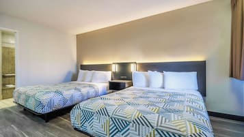 Una habitación de hotel con dos camas, una mesita de noche y un aplique de pared.