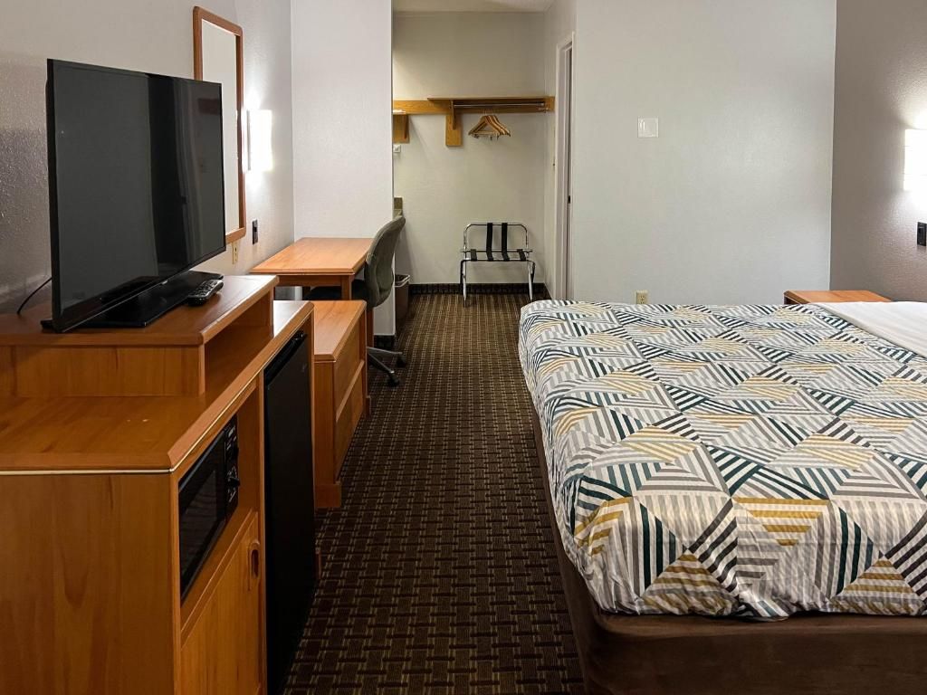 Une chambre d’hôtel équipée d’un lit, d’un bureau, d’une chaise, d’une télévision et d’une armoire.