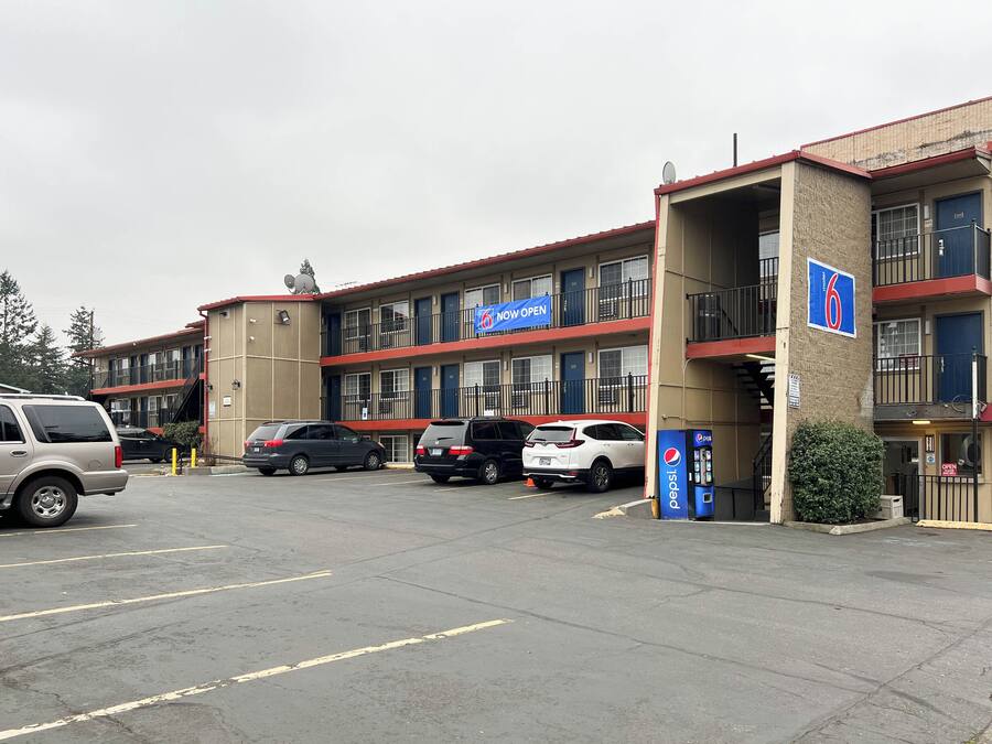 A motel with a parking lot, multiple cars, and a Pepsi vending machine.