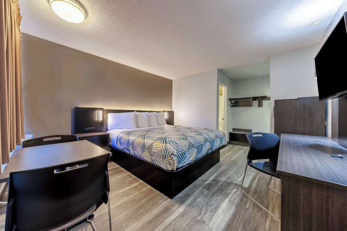 Une chambre d’hôtel avec un lit, un bureau, une chaise et un téléviseur.