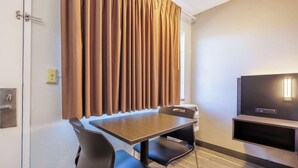 A hotel room with a dining table, chairs, a flat-screen TV, and a window with curtains. - Motel 6 Portland, OR - Southeast (Portland)