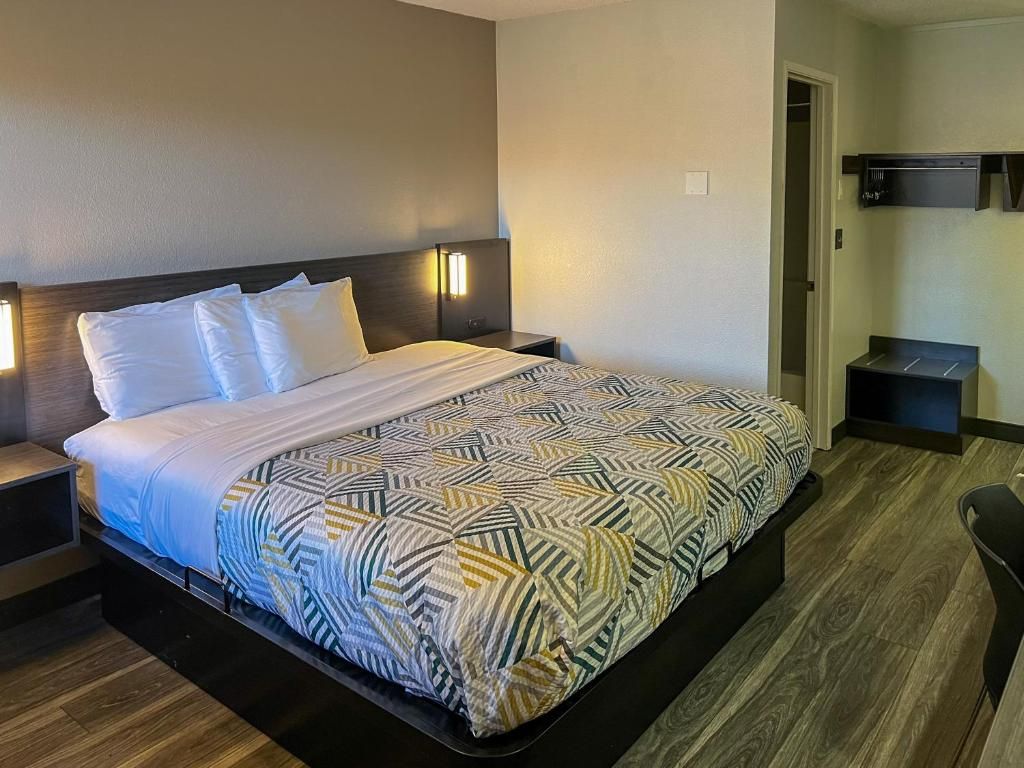 A hotel room with a bed, bedside tables, a chair, and a wardrobe.
