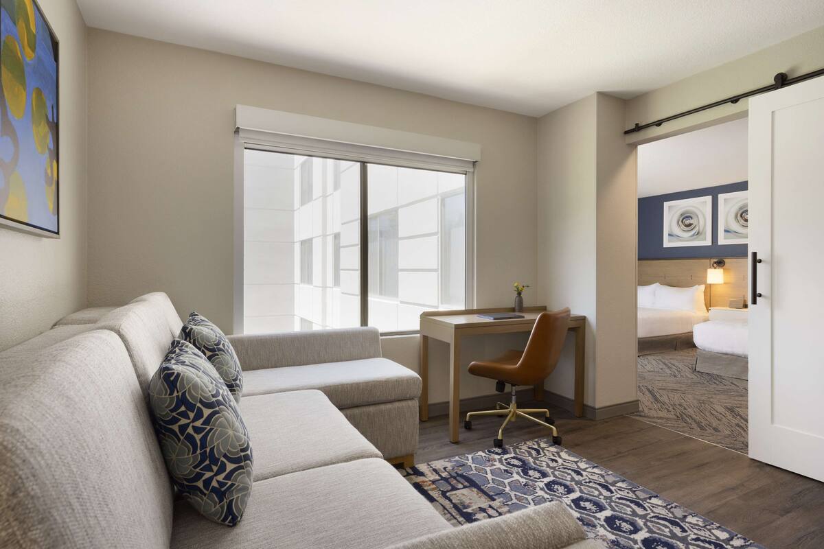 Une chambre d’hôtel avec un canapé, un bureau, une chaise, un tapis à motifs et un lit.