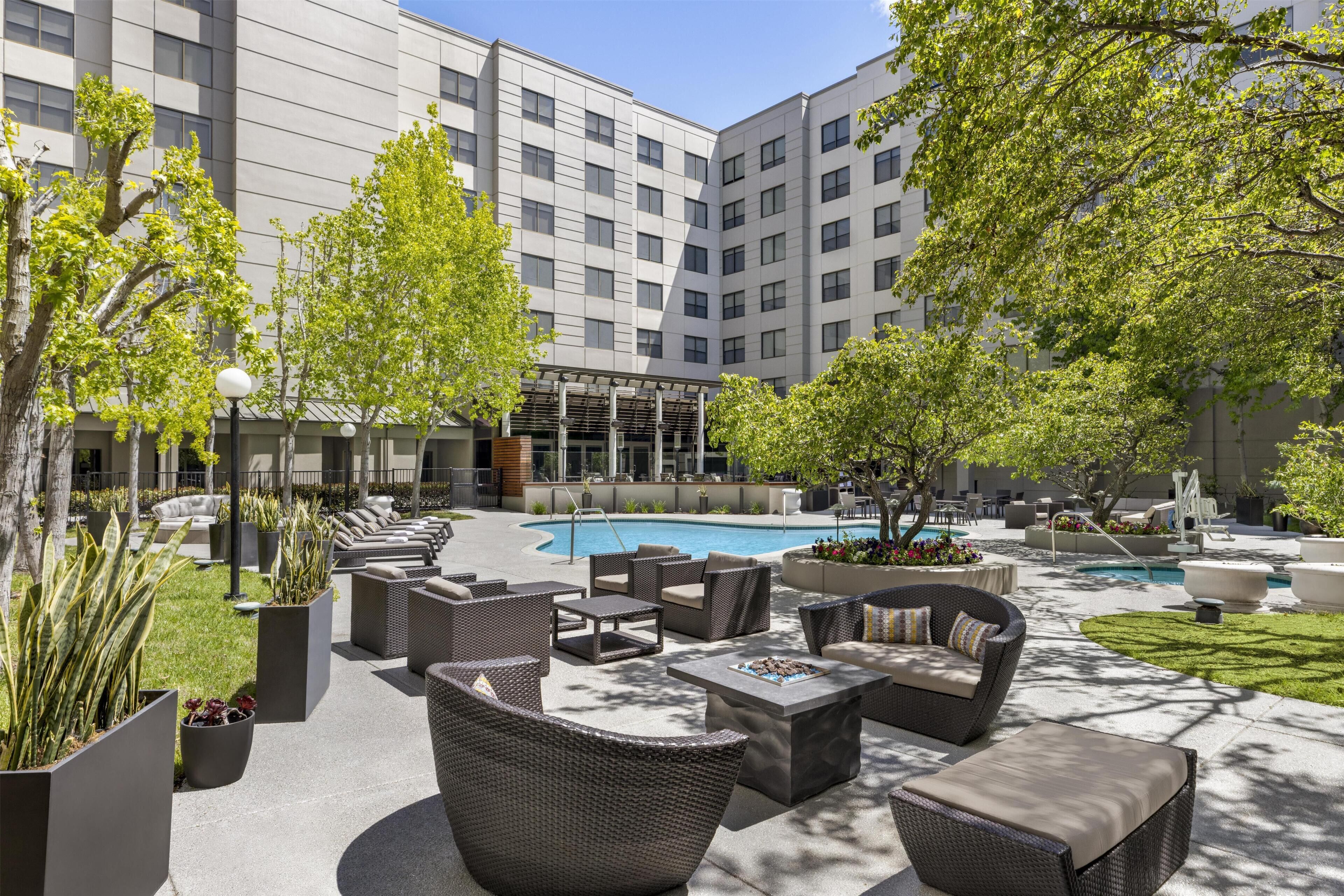 A rooftop pool area with outdoor seating and a view of a modern building.