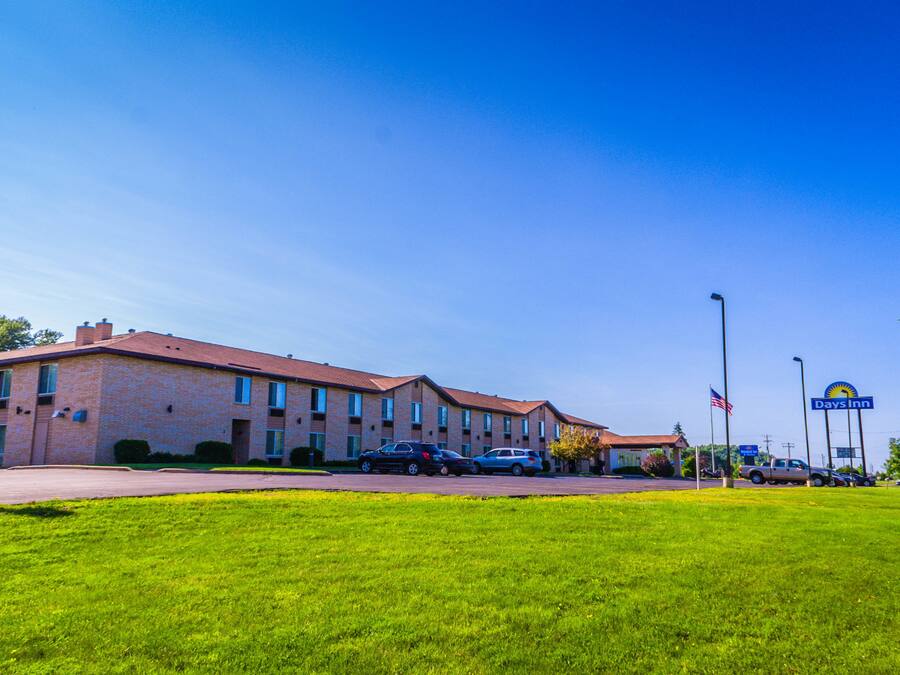 A Days Inn with a brick building, multiple parking spaces, and a clear blue sky.