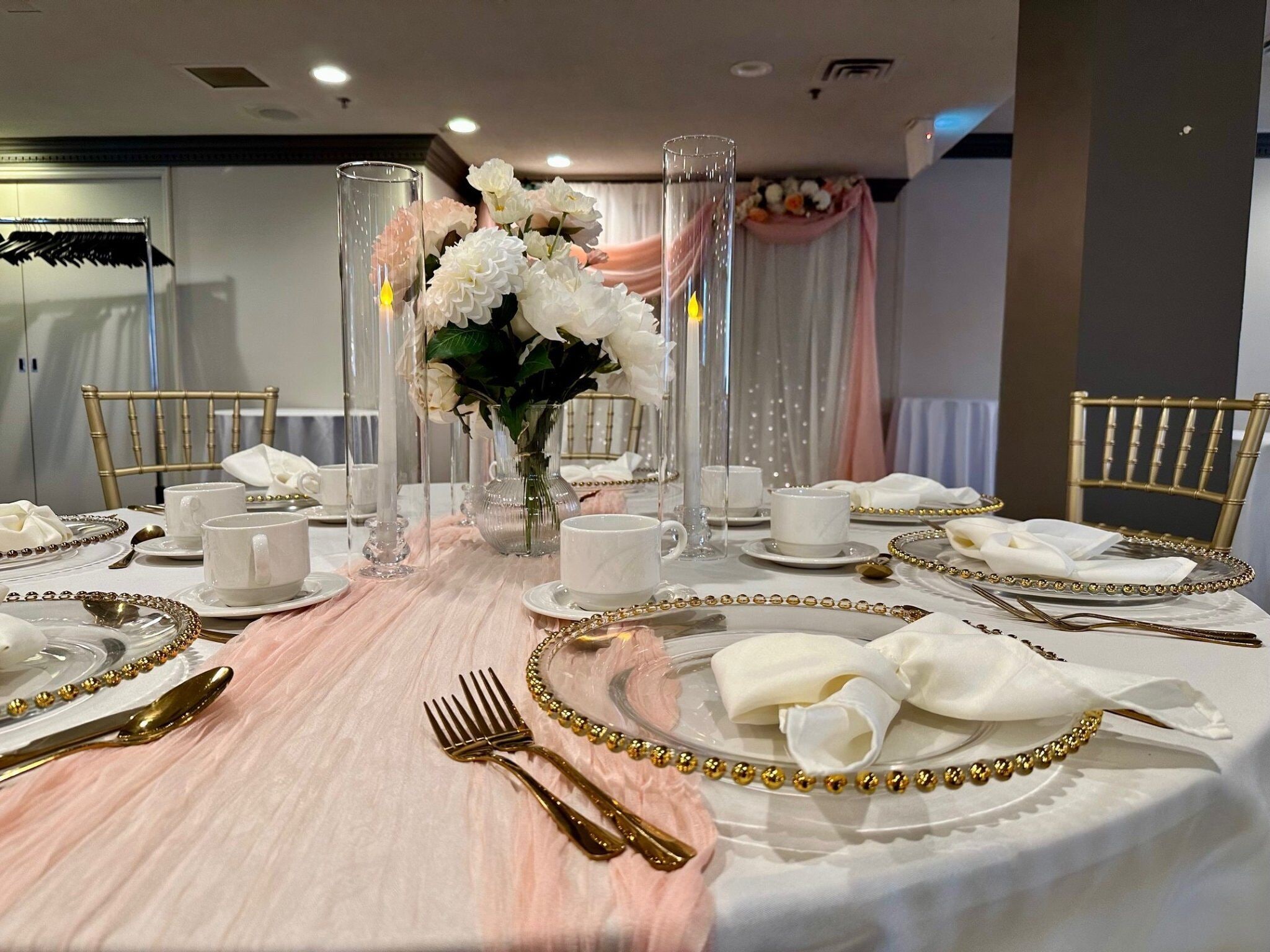 Une table à manger élégante, dressée avec de la vaisselle blanche et dorée, comprenant des assiettes, des tasses et des couverts.