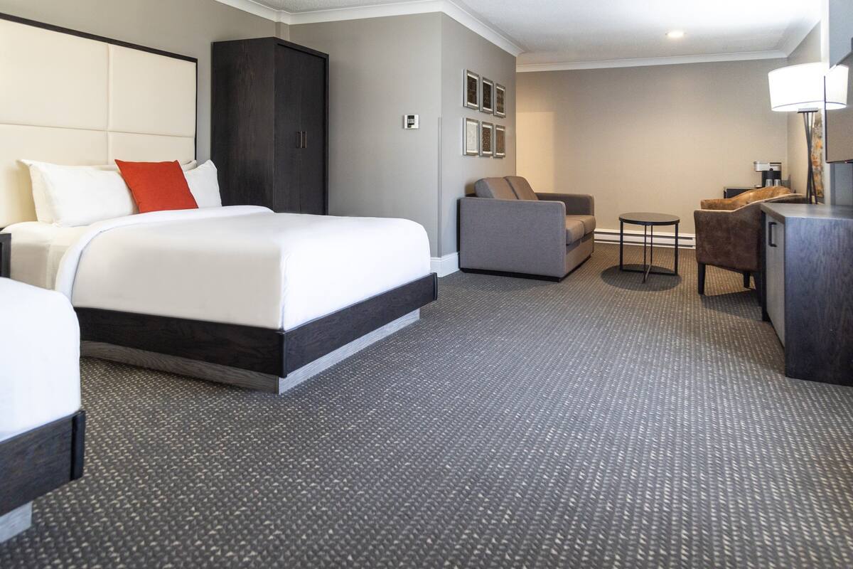 A hotel room with a large bed, a sofa, a desk, and a chair.
