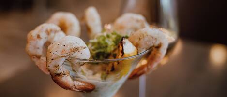 A martini glass with grilled shrimp and a garnish.