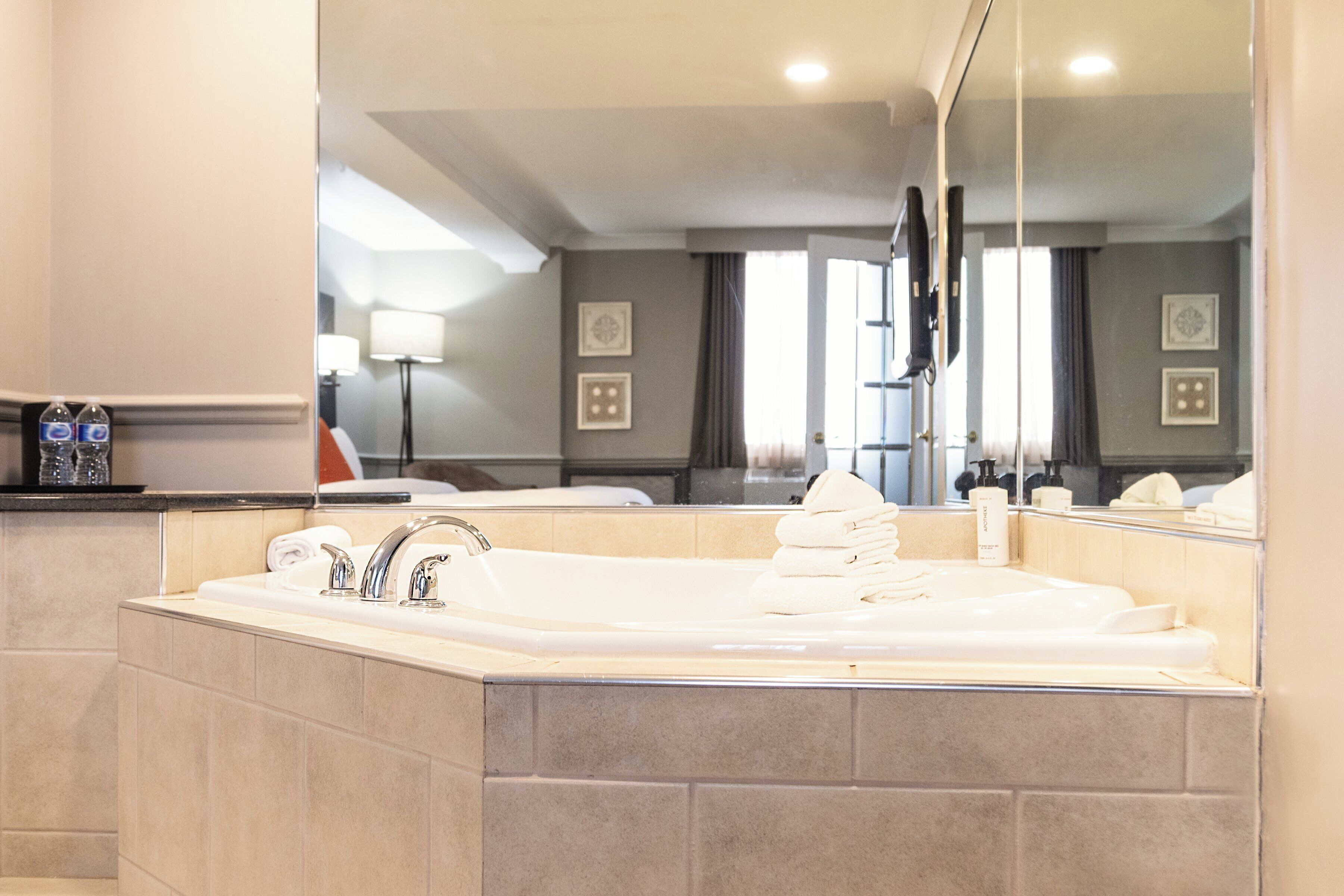 A modern bathroom with a large bathtub, a sink, and a mirror.