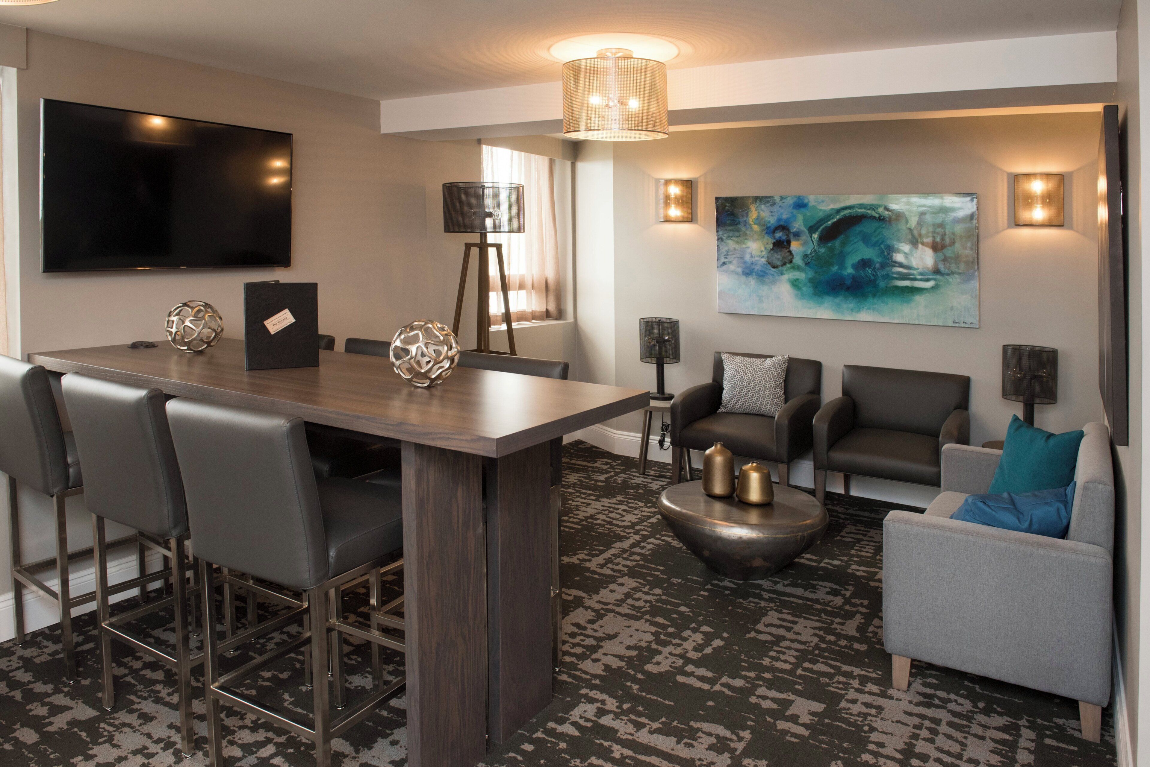 A modern living room with a bar area, seating, and artwork.