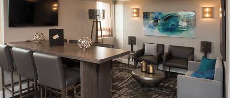 A modern living room with a bar area, seating, and artwork.