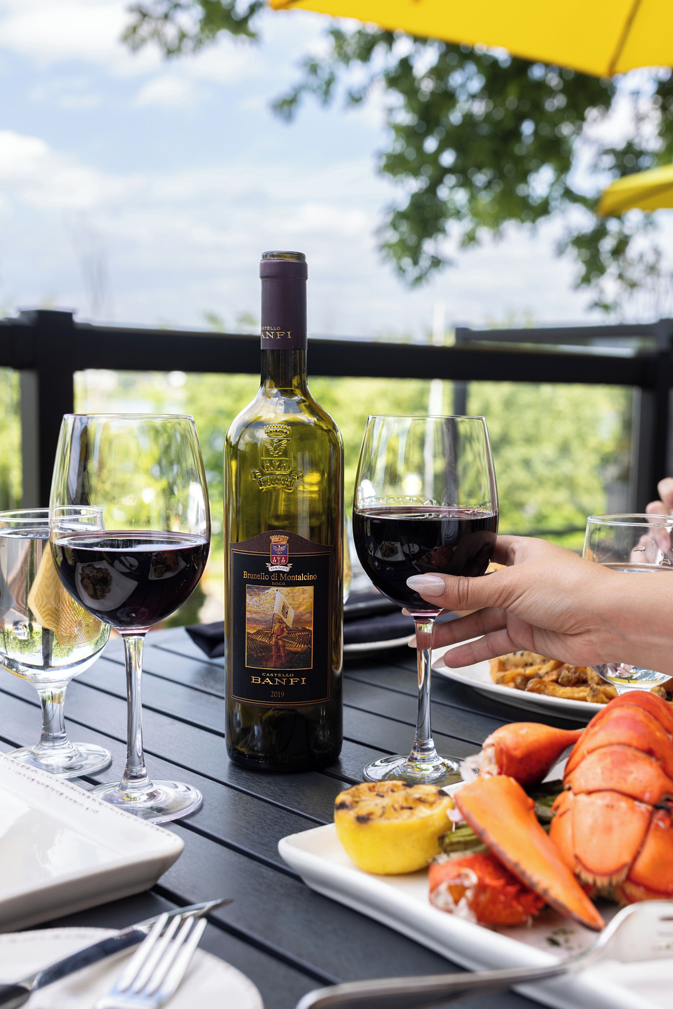 A table with a bottle of wine, glasses, and a lobster tail.