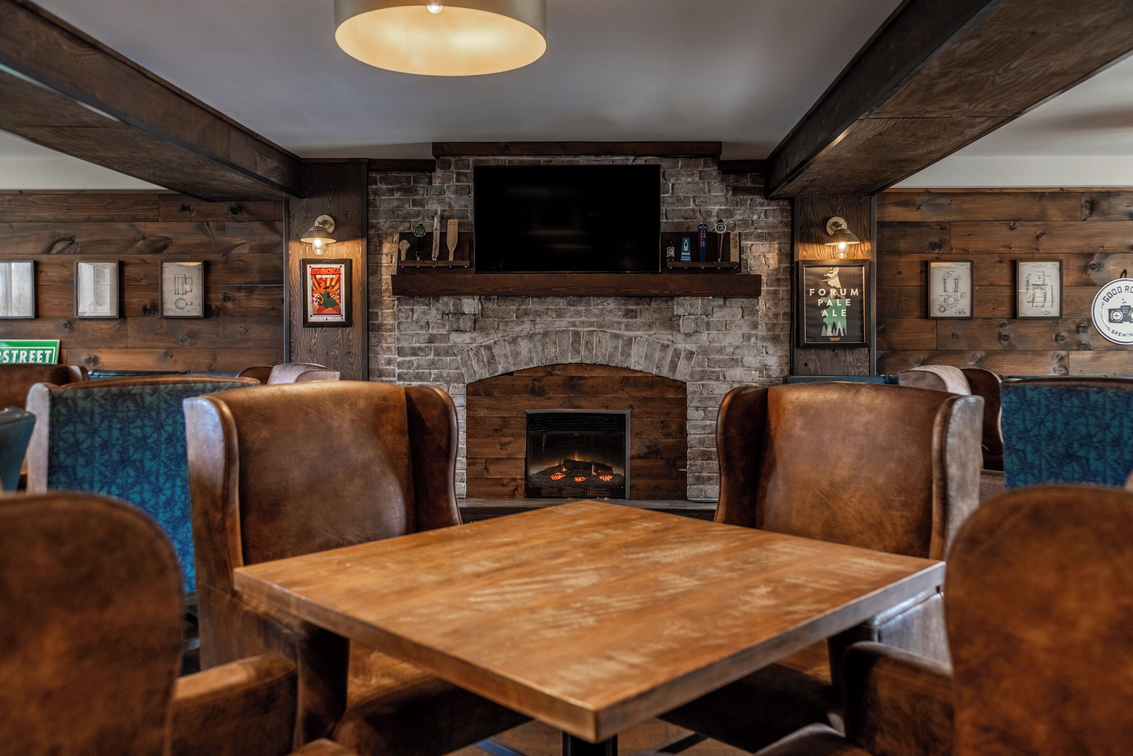 Un restaurante con chimenea de piedra, vigas de madera y cabinas de cuero.