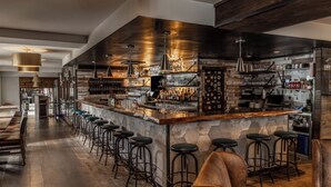 Una zona de bar con una barra larga, taburetes y una pared de piedra.