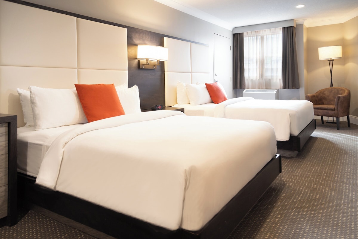 Een hotelkamer met twee bedden, een bureau, een stoel en een lamp.
