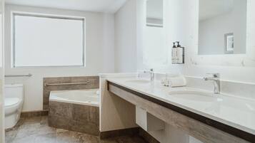 Un baño moderno con un ventanal grande, dos lavamanos, una bañera y un inodoro.