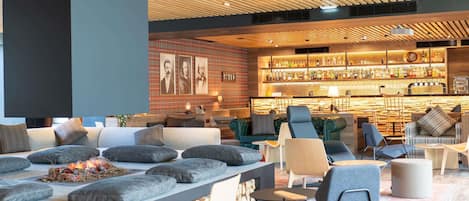Un espace de détente moderne, doté de sièges confortables, d’une cheminée et d’un bar proposant un large choix de boissons.