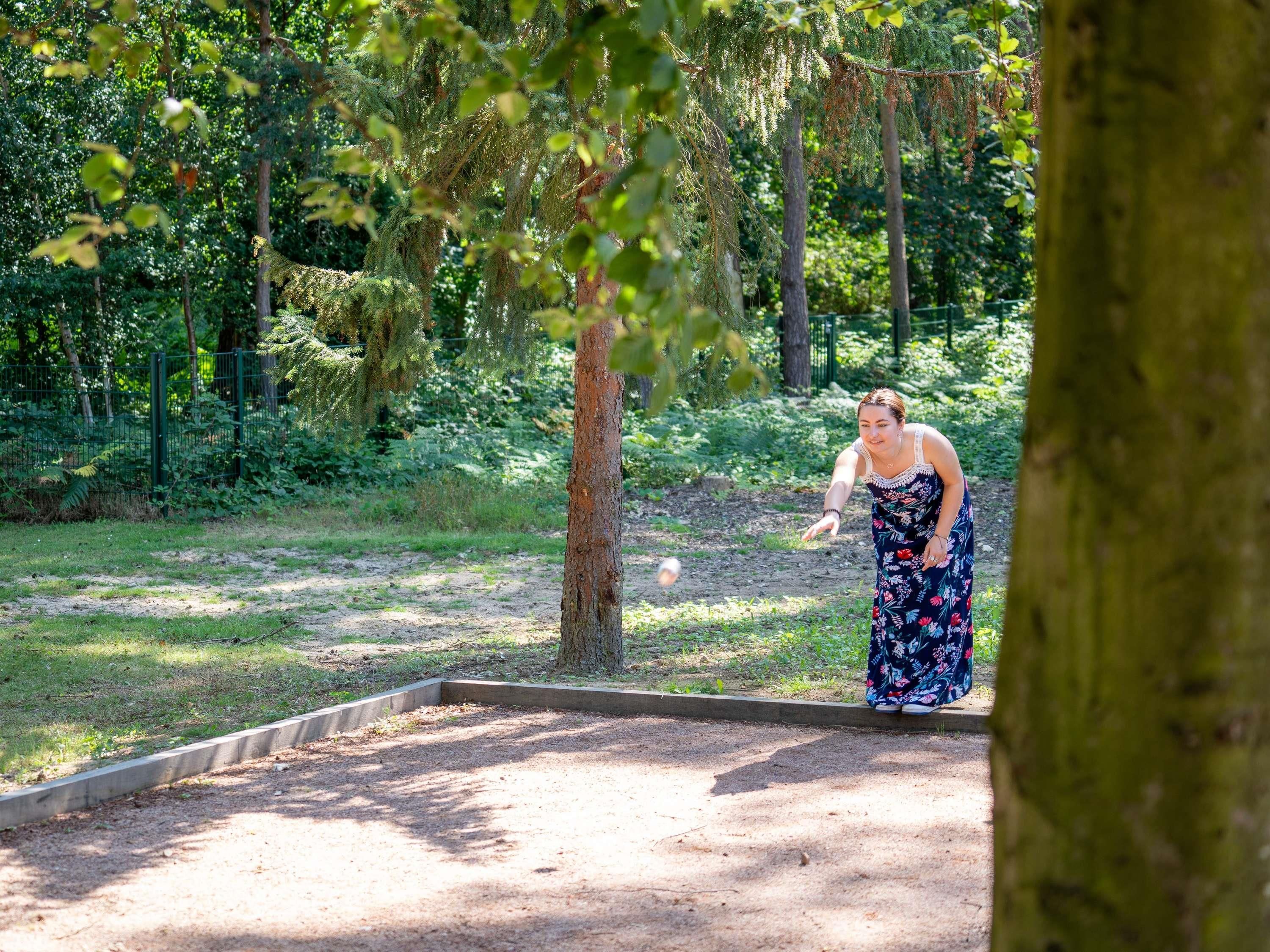 Una persona con un vestido estampado está de pie en una zona boscosa con un sendero de tierra.