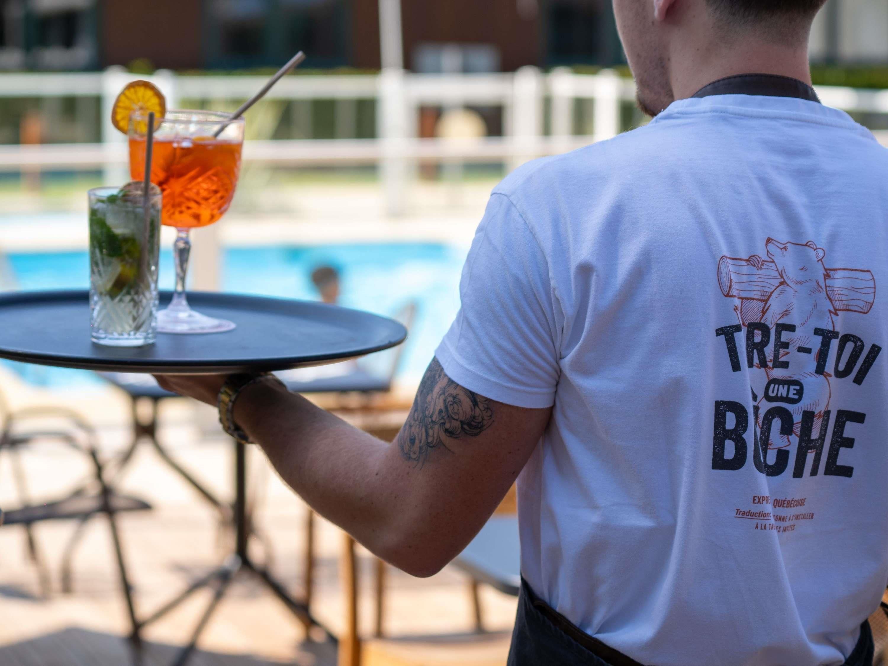 Iemand serveert drankjes bij een buitenzwembad.