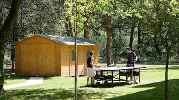 Un cobertizo de madera en un parque con una mesa de ping pong cerca.