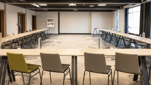 A conference room with a long table, multiple chairs, and a projector screen.