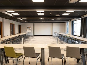 Un salón de conferencias con una larga mesa, varias sillas y una pantalla para proyector.