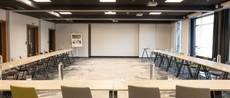 A conference room with a long table, multiple chairs, and a projector screen.
