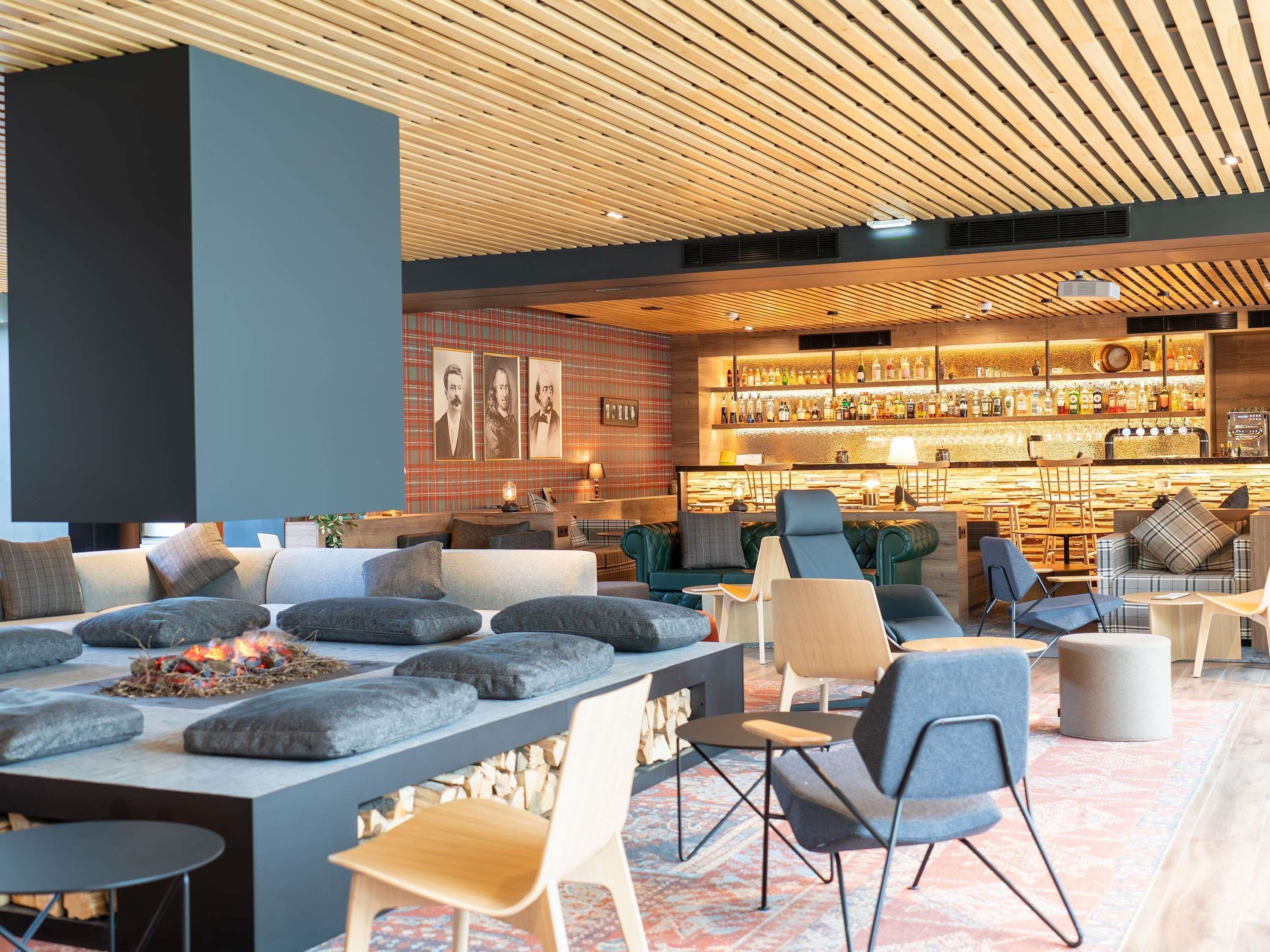 Uma área de estar moderna com assentos, lareira e bar com diversos tipos de bebidas.
