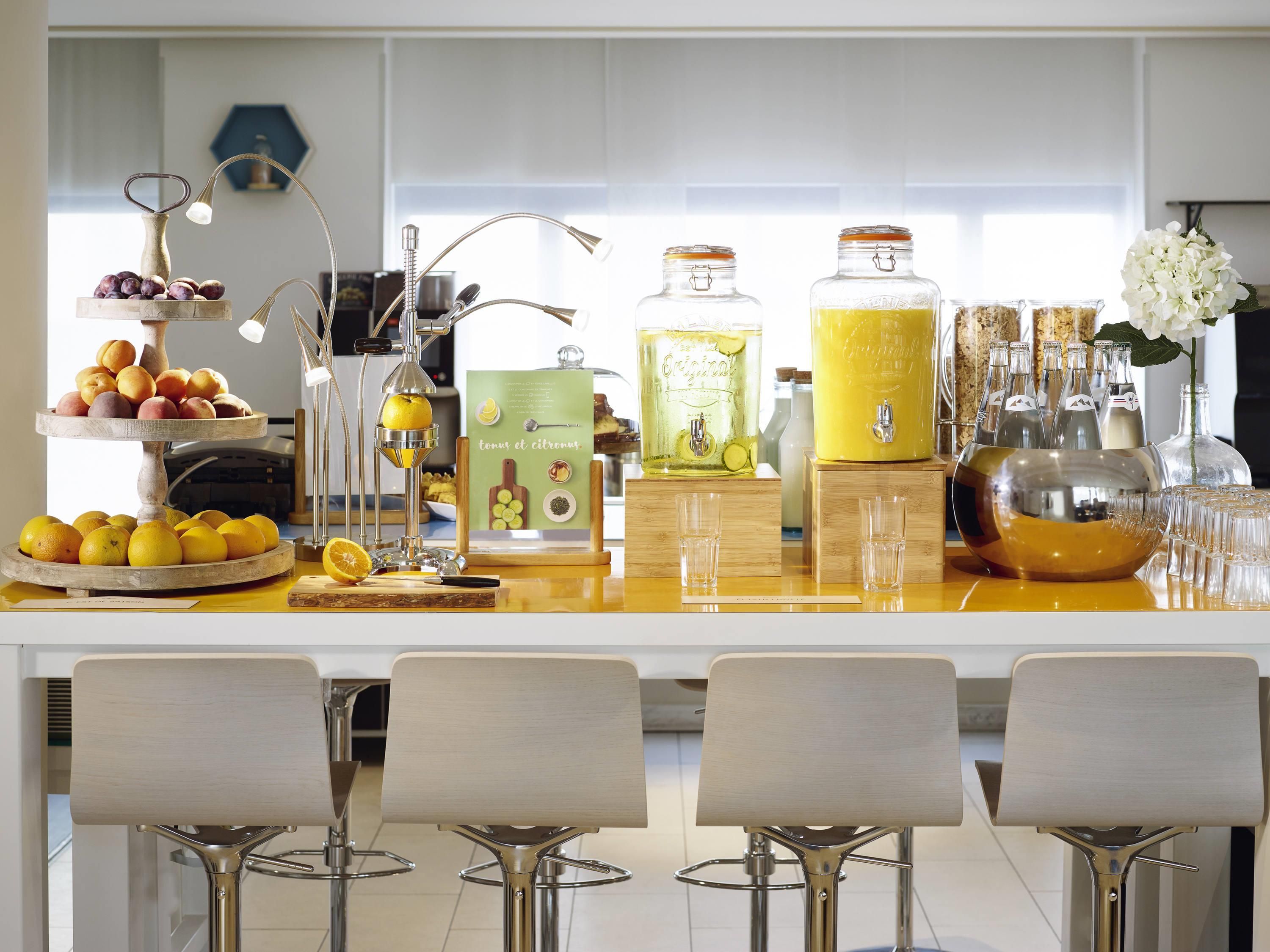 A bar area with a fruit display, a juice dispenser, and bar stools.