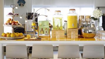 A bar area with a fruit display, a juice dispenser, and bar stools.
