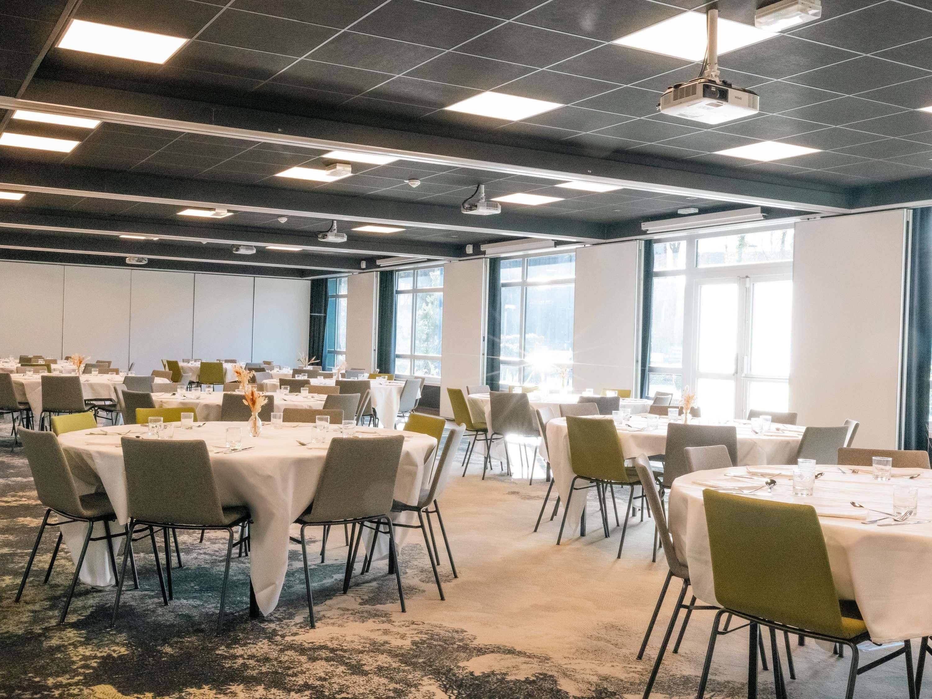 A conference room with multiple tables, chairs, and a projector.
