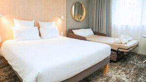 Habitación de hotel con dos camas, un espejo grande y vista al exterior.