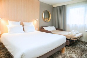 Habitación de hotel con dos camas, un espejo grande y vista al exterior.
