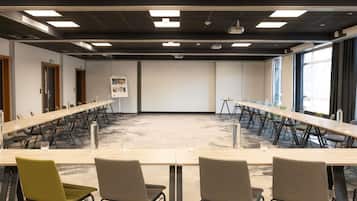 Ett konferensrum med ett långt bord, flera stolar och en projektorduk.