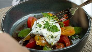 A bowl of food with a fork, containing vegetables and a dollop of sauce.