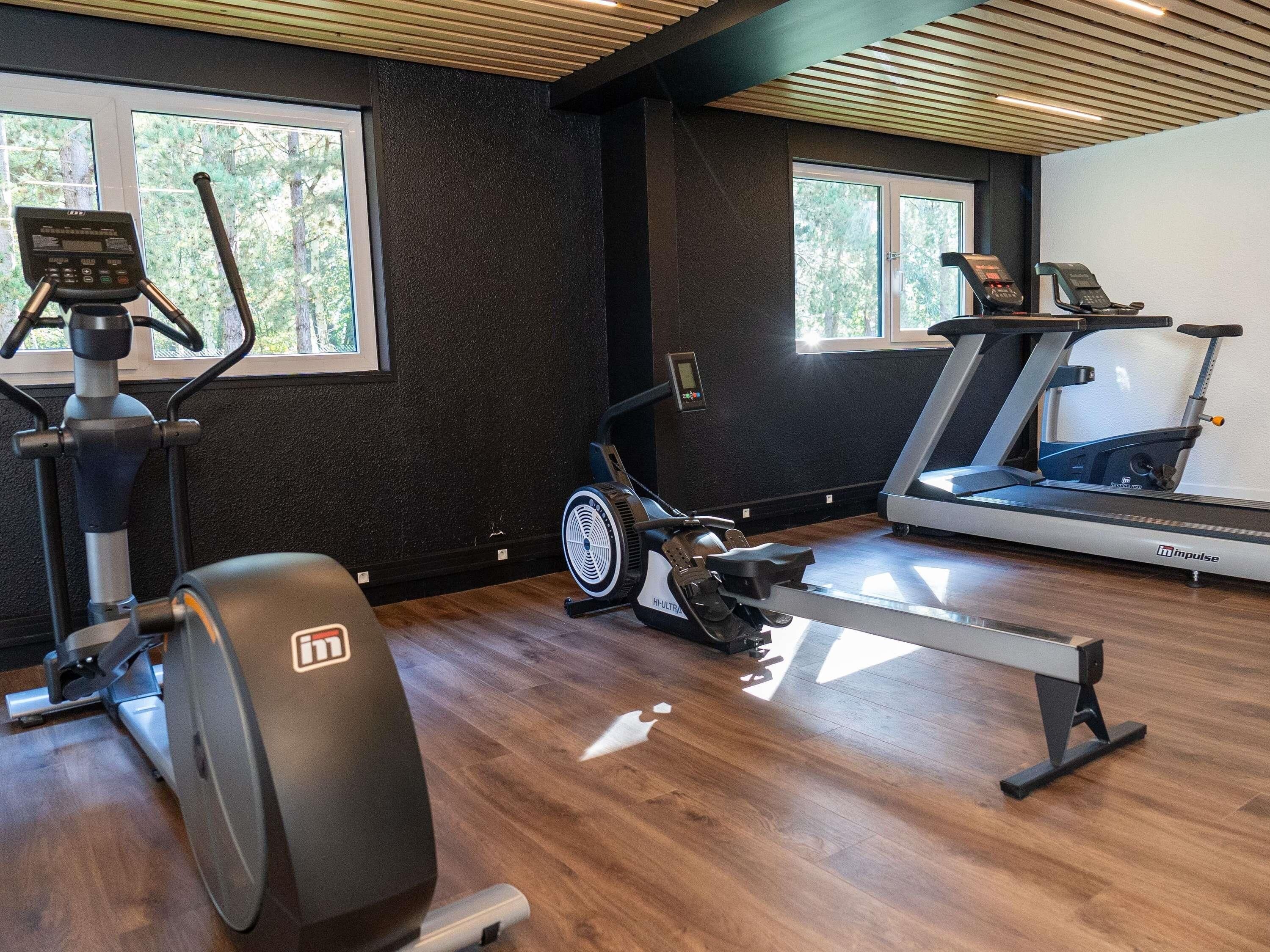 Une salle de sport équipée de machines de cardio, d’un rameur et d’un tapis de course.