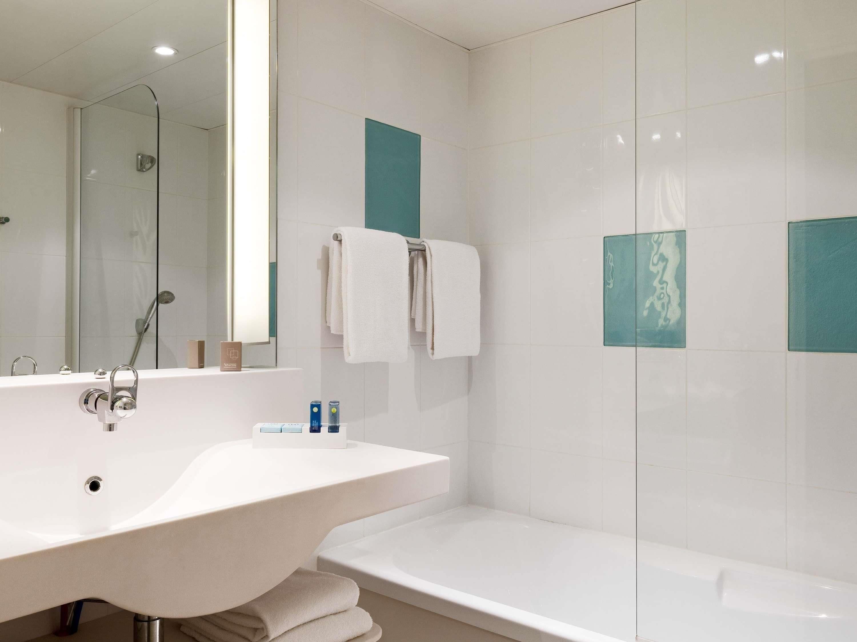 Un baño moderno con un lavamanos grande, un espejo, cabina de ducha con mampara de vidrio y una bañera.