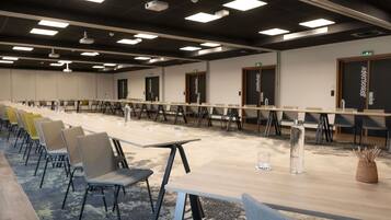 A conference room with long tables, chairs, and a carpeted floor.