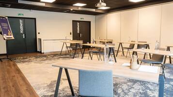 Een vergaderruimte met tafels, stoelen, een beamer en een vloerkleed.