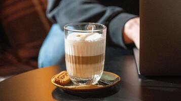 Una taza de café sobre un posavasos, junto a una computadora portátil sobre una mesa.